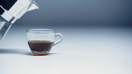 coffee maker near glass cup with coffee on white and grey.