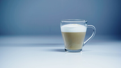 coffee latte with white foam in glass on grey.