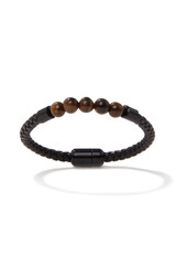 Detailed shot of a black bracelet. The hand accessory is with brown beads. The bracelet has a braided surface. The accessory is isolated on the white background.