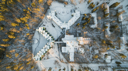 Aerial view of the postmodern sanatorium building surrounded by forest. Winter sunny day