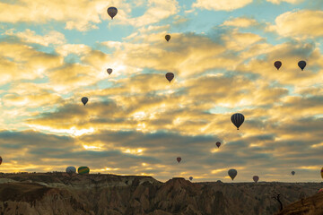 Hot air balloons flying over spectacular Cappadocia. Beautiful view of hot air balloons floating in sunrise blue sky over the mountain landscape of fairy chimneys