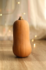 Butternut squash on wooden table, bokeh lights in the background. Selective focus.