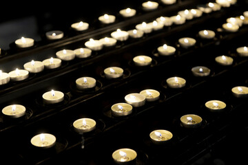 Lots of lit small candles in the catholic church, selective focus, close-up.