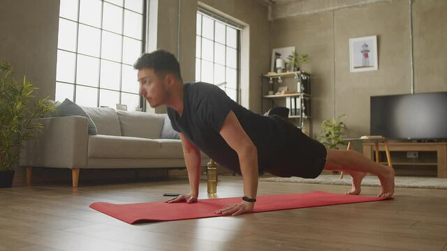Young caucasian man doing floor push-ups at home