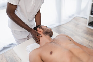 Fototapeta na wymiar african american chiropractor treating young man in rehabilitation center
