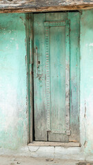 old and weathered or worn green wooden door of village house.