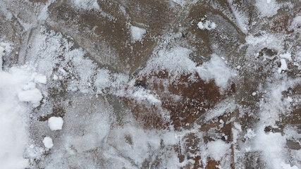 Surface of natural stone under snow in winter. Top view. Selective focus.