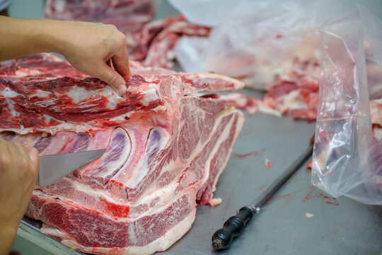 Close-up of raw meat cutting with a knife in an abattoir doing butchering and trimming of wagyu beef in the meat industry. Wagyu beef slices in beef cattle restaurants in many parts of Japan.