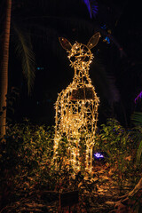 Animal con luces de navidad entre plantas de noche