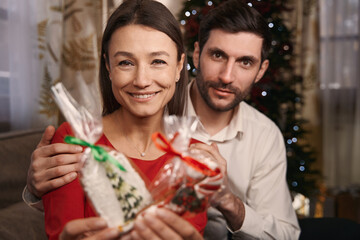 Happy man and woman showing sweets and posing for the camera