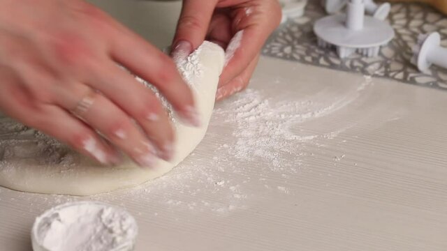 A woman makes confectionery mastic from powdered sugar. Kneads it with his hands, adds powdered sugar. Close-up