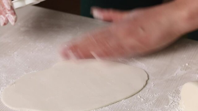 A woman makes confectionery mastic from powdered sugar. I rolled out the mastic and cut out figures from it. Close-up
