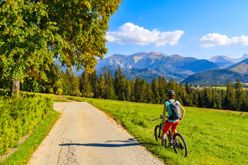 Young woman on bike looking at beautiful panorama of Tatra Mountains, Poland © pkazmierczak