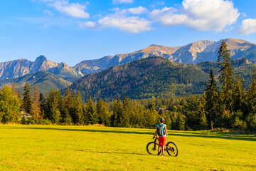 Young woman on bike looking at beautiful panorama of Tatra Mountains, Poland - 477308670