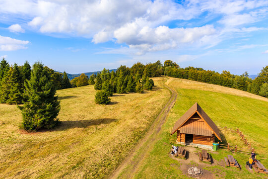 BRENNA, POLAND - SEP 26, 2021: Beautiful wooden hut on green meadow near Stary Gron observation tower with view Silesian Beskid Mountains, Brenna, Poland.