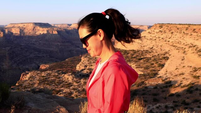 Asian woman hiking along the edge of the San Rafael River Canyon in Utah also called the Little Grand Canyon