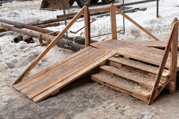 temporary wooden bridge over the pipe. Repair of the heating system
