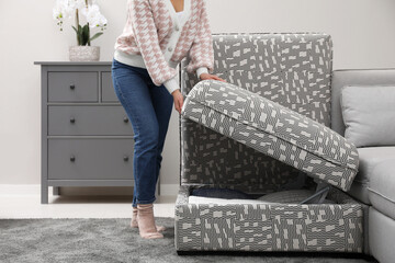 Woman closing modular sofa section with storage in living room, closeup