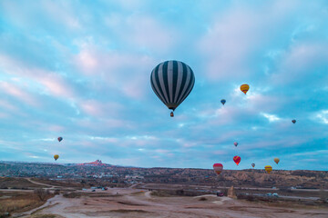 Hot air balloons flying over spectacular Cappadocia. Beautiful view of hot air balloons floating in sunrise blue sky over the mountain landscape of fairy chimneys