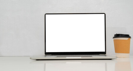 Mockup of laptop with blank white screen on table with coffee cup