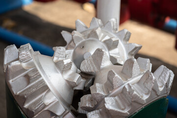 A polycrystalline carbide drill bit, using for drill a subsurface rock structure in oil drilling operation. Oil industrial heavy equipment object photo. Close-up and selective focus.