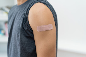 Close up - plaster on strong arm of man after third vaccination against Covid 19