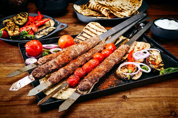 Traditional Turk Adana kebap on shashlik skewer with barbecue vegetable, flatbread and yogurt as...