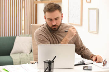 Young man working with laptop at home