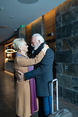 Elderly wife and husband hugging in a hotel