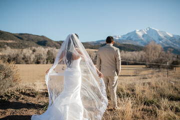 Fototapeta na wymiar First meet of the bride and groom outdoors Groom waits for his beloved Bride holds her white veil Mountains background