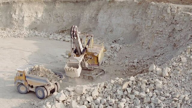 An excavator loads soil into a mining dump truck. Equipment for the extraction of iron ore in a quarry. The process of mining iron ore in a quarry. The smart process in an iron ore quarry