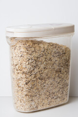 oatmeal flakes in a plastic food container jar with white lid isolated on white background