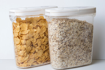 oatmeal flakes and corn flakes in plastic food container jars with white lid isolated on white...
