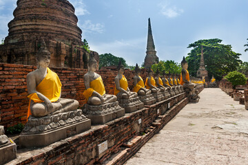 Fototapeta na wymiar Aligned Sitting Buddha Statues at Wat Yai Chaimongkol in Ayutthaya, the 13 century historic capital of Kingdom of Siam, Thailand