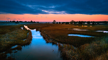 Fototapeta na wymiar Dramatic twilight seascape over the marshland river at South Cape Beach in Mashpee, Massachusetts.