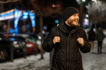 male tourist with a backpack walks through the night city in winter. got lost