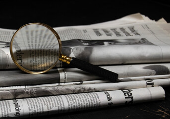 Magnifying glass and newspapers. Concept for fact check, detective search