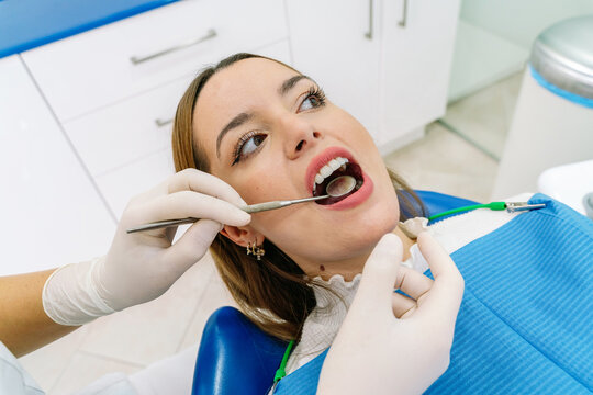 Unrecognizable dentist examining teeth of woman