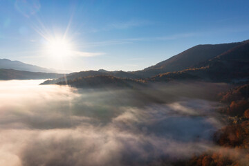 Sunset light among clouds above mountainous canyon in mist