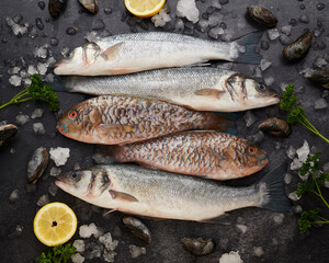 Assorted raw fish and mussels placed on table with lemons and herbs