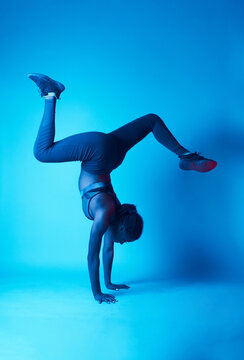Graceful black female model performing handstand with split legs