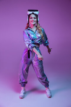 Smiling female in stylish outfit dancing in studio with neon lights
