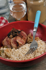 Paupiette de veau aux pruneaux avec du riz servis dans une assiette avec une fourchette et un verre d'eau en gros plan