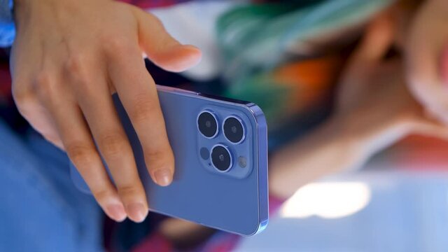 Vertical stock video of girl using modern smartphone in hand. Young female browsing social media news feed on mobile phone with three cameras. Royalty free footage of new cellphone with triple cameras