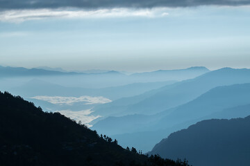 Sunrise scene as seen from Okhrey, Sikkim, India. Sun rising from the back of mountain , blue fog...