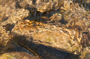 Sunrays reflecting from stones and rocks underwater - creating beautiful abstract natural pattern. Image shot at Reshi river, Sikkim, India