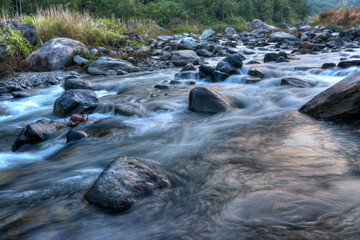 Naklejka na ściany i meble Beautiful Reshi River water flowing through stones and rocks at dawn, Sikkim, India. Reshi is one of the most famous rivers of Sikkim flowing through the state and serving water to many local people.