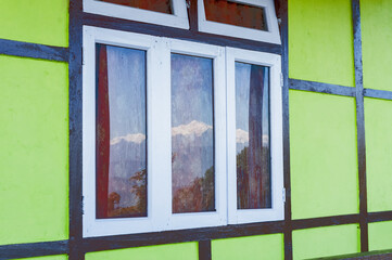 Fototapeta premium Beautiful reflection of snowy Mount Kanchenjungha on glass window , wet with dew drops. Image of Himalayan mountain range, Sikkim, India.