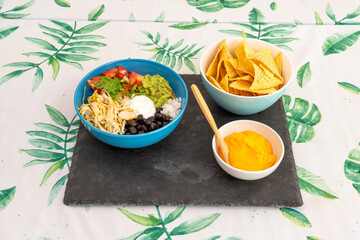Full Mexican menu of black beans with pulled chicken, queso fresco, avocado, chopped tomato, melted cheddar cheese and corn chips
