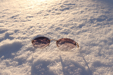 Sunglasses are lying on the snow. Protect your eyes from UV light in winter.